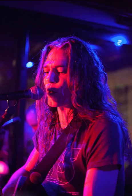 Male singer with long hair gazing to microphone and singing onstage at private performance | Altus Entertainment