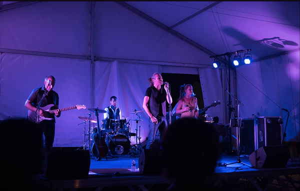 Photo taken from audience of four person pop rock band in France performing onstage at outdoor party | Altus Entertainment