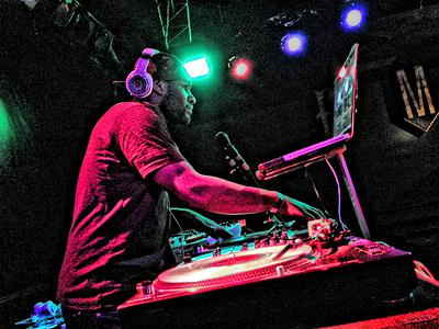 Low angled picture of DJ Washington DC mixing music and looking at laptop at indoor private event | Altus Entertainment