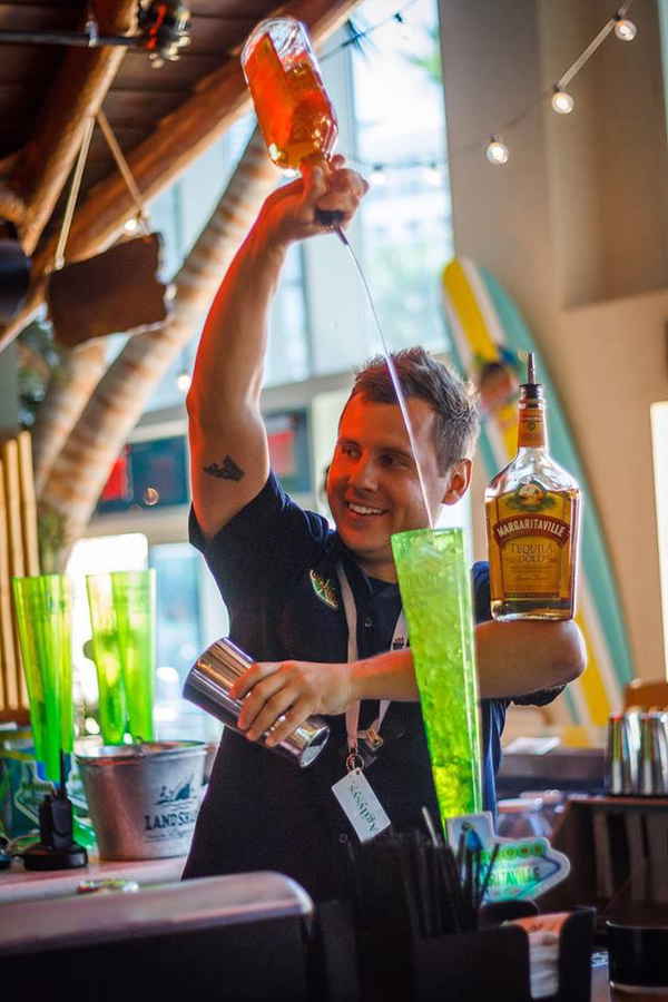 Professional picture of flair bartender looking to side pouring drink and balancing another bottle | Altus Entertainment