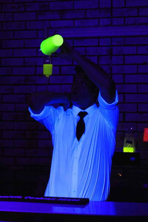Male Las Vegas flair bartender pouring glow in the dark cocktail into glass balancing on arm | Altus Entertainment
