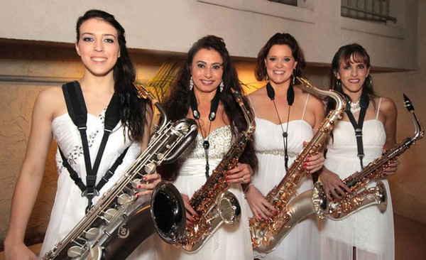 All female horn musicians in our yacht rock band for parties wearing all white dresses and smiling for picture | Altus Entertainment