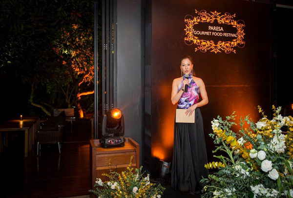 Female event emcee in Thailand looking to camera while hosting Paresa Gourmet Food Festival | Altus Entertainment