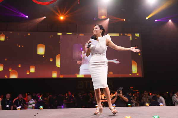 Picture taken from audience of event emcee in Thailand walking across stage and talking happily to audience during event | Altus Entertainment