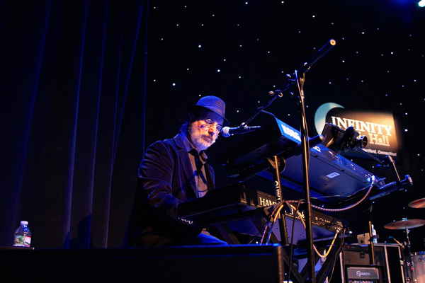 A man in a hat playing a keyboard on stage | Altus Entertainment